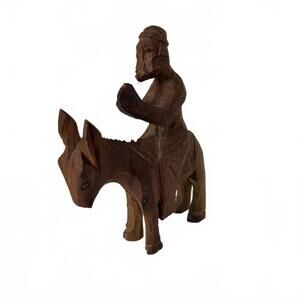 Small hand-carved wooden figurine of a man riding a donkey.